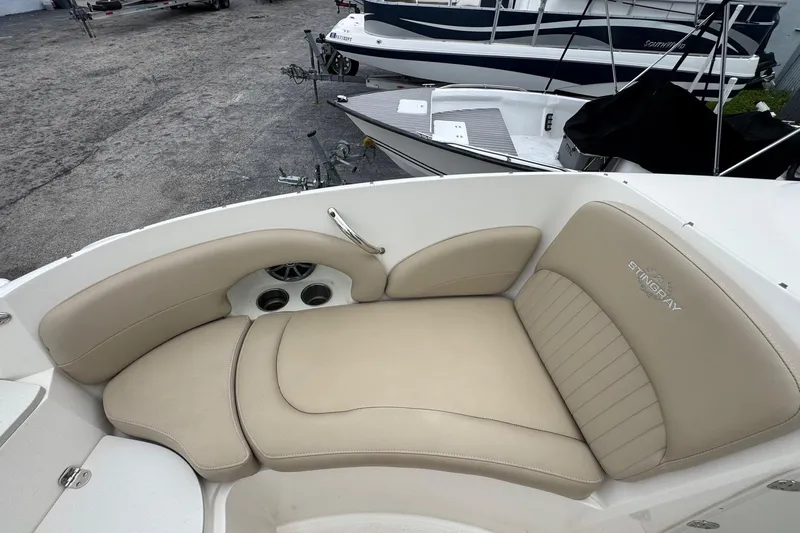 Slide: The Image of 2015 Stingray 215 LR boat interior with beige seating and cup holders. - 25