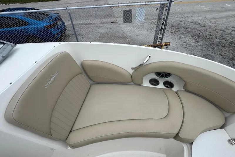 Slide: The Image of 2015 Stingray 215 LR boat interior with beige seating and cup holders. - 27