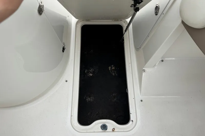 Slide: The Image of Open storage compartment on 2015 Stingray 215 LR boat, featuring a black interior. - 31