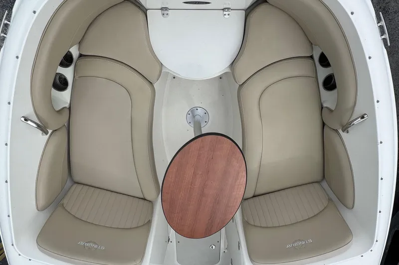 Slide: The Image of 2015 Stingray 215 LR boat interior with beige seating and wooden table. - 6
