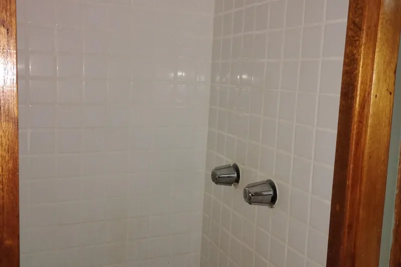 Slide: The Image of Shower area with white tiles and dual chrome knobs on a 1983 Custom Entienne Francois 50 Pilothouse. - 34