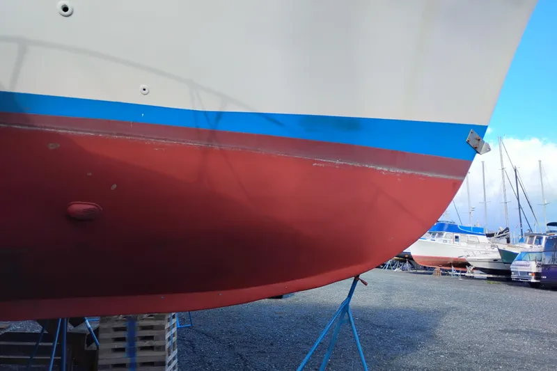 Slide: The Image of 1983 Custom Entienne Francois 50 Pilothouse boat hull in dry dock, red and blue paint. - 46