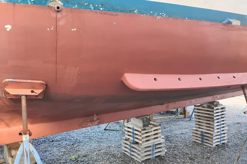 Slide: The Image of Hull of 1983 Custom Entienne Francois 50 Pilothouse on blocks, showing red and blue paint. - 49