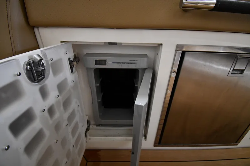 Slide: The Image of 2020 Sea Ray SLX 400 Outboard interior with open mini fridge and storage compartment. - 25