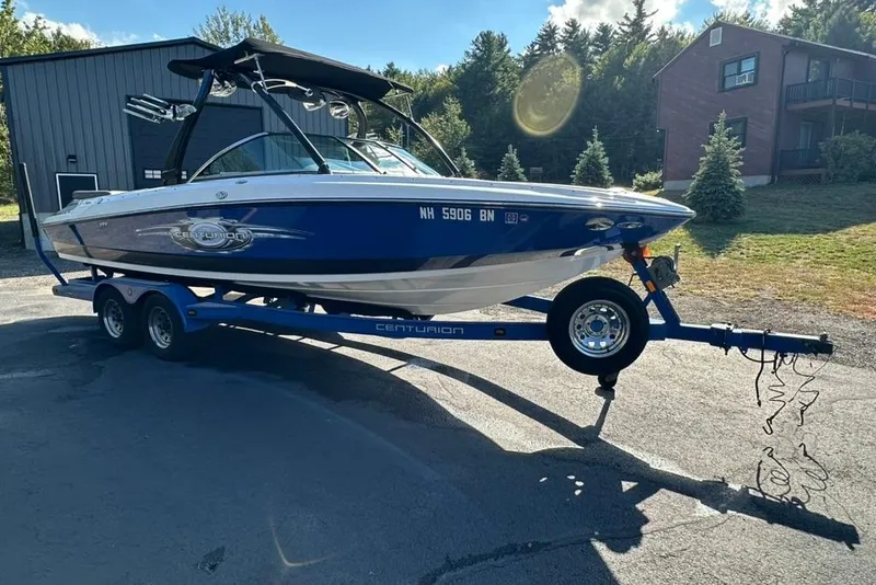 Slide: The Image of 2006 Centurion Enzo SV230 boat on trailer, parked outdoors, with trees and buildings in background. - 4