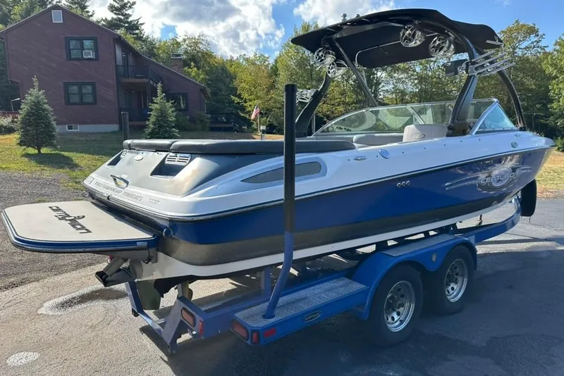 Slide: The Image of 2006 Centurion Enzo SV230 boat on trailer, parked near a house with trees. - 6