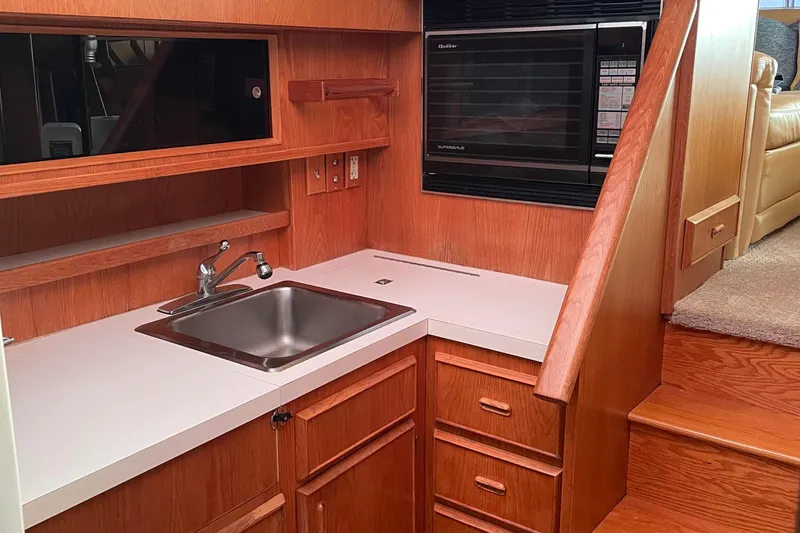 Slide: The Image of 1987 Bertram 42 Convertible yacht kitchen with sink, microwave, and wooden cabinetry. - 9