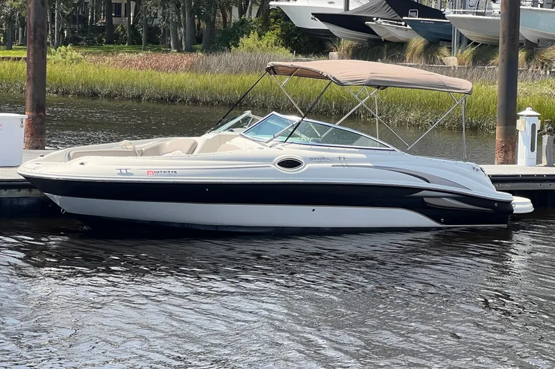 Slide: The Image of 2003 Sea Ray 240 Sundeck boat docked on calm water with a canopy. - 1