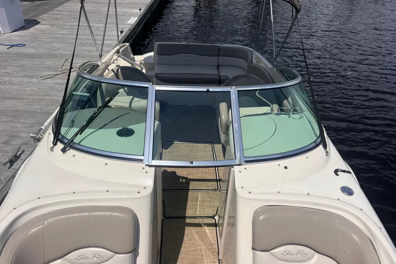 Slide: The Image of 2003 Sea Ray 240 Sundeck boat with spacious seating, docked by calm water. - 6