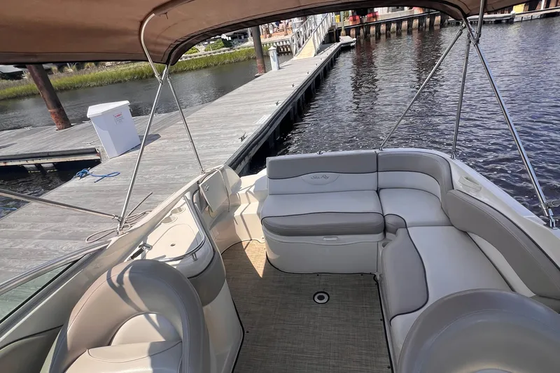 Slide: The Image of 2003 Sea Ray 240 Sundeck boat interior with steering wheel and seating, docked by the water. - 8