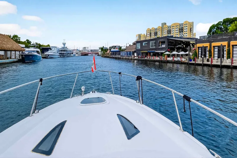 Slide: The Image of 2007 Sea Ray 290 Sundancer cruising in a vibrant marina with waterfront buildings. - 13