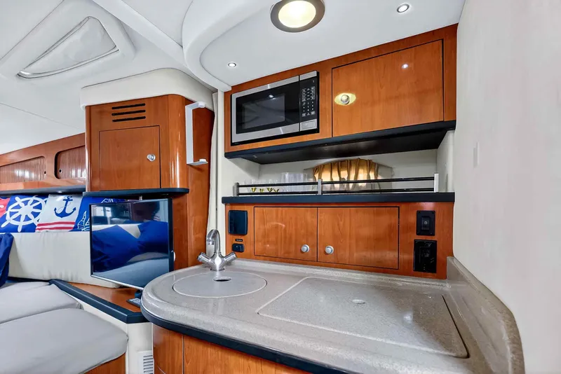 Slide: The Image of 2007 Sea Ray 290 Sundancer interior with kitchenette, microwave, and nautical-themed decor. - 28