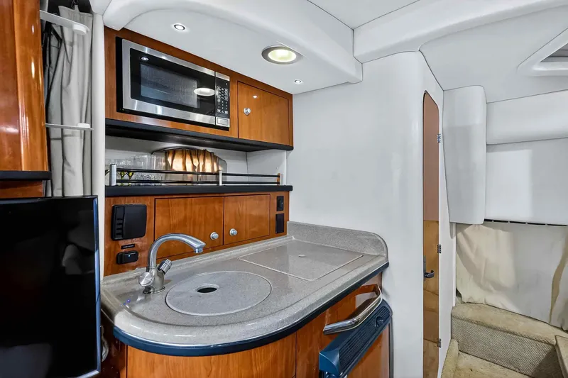 Slide: The Image of 2007 Sea Ray 290 Sundancer interior with kitchenette, featuring microwave and sink. - 31