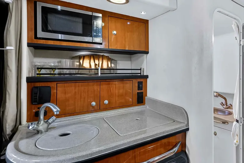 Slide: The Image of 2007 Sea Ray 290 Sundancer galley with microwave, sink, and wooden cabinetry. - 32