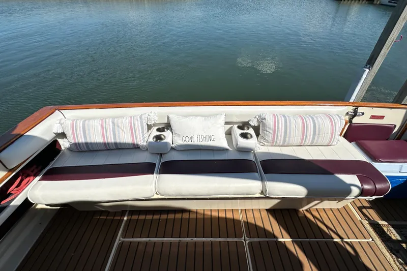 Slide: The Image of 1987 Sea Ray 340 Sundancer boat interior with cushioned seating and "Gone Fishing" pillow. - 12