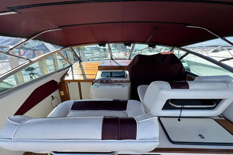 Slide: The Image of 1987 Sea Ray 340 Sundancer interior with white and maroon seating, docked at marina. - 14