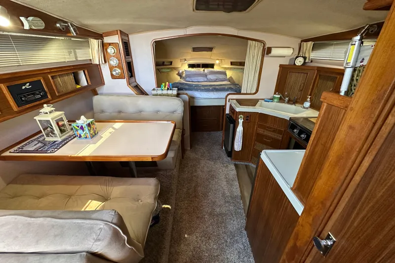 Slide: The Image of Interior of 1987 Sea Ray 340 Sundancer with cozy seating, dining area, and kitchenette. - 24