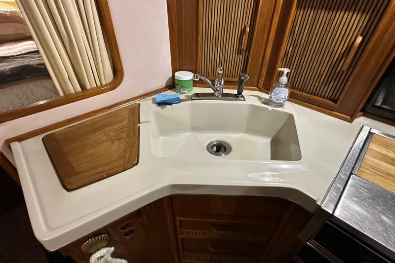 Slide: The Image of 1987 Sea Ray 340 Sundancer kitchen sink area with wooden accents and countertop accessories. - 27