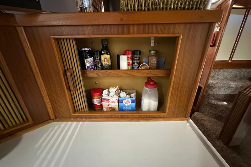 Slide: The Image of Wooden cabinet with spices and condiments inside a 1987 Sea Ray 340 Sundancer boat. - 31