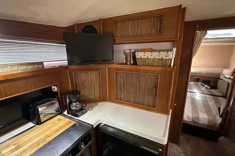 Slide: The Image of 1987 Sea Ray 340 Sundancer interior with kitchenette, TV, and cozy sleeping area. - 32