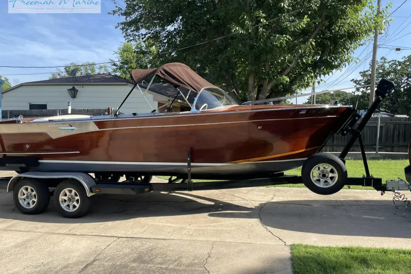 Slide: The Image of 1964 Shepherd 22 boat on trailer, polished wood finish, parked in driveway. - 10