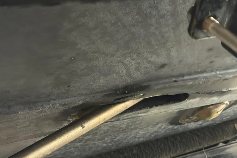 Slide: The Image of Close-up of a 1964 Shepherd 22 boat hull with visible damage and metal rod. - 26