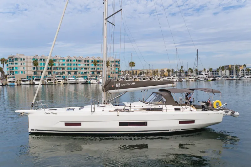 Slide: The Image of 2024 Dufour 470 sailboat docked in marina, modern design, calm water, blue sky. - 1