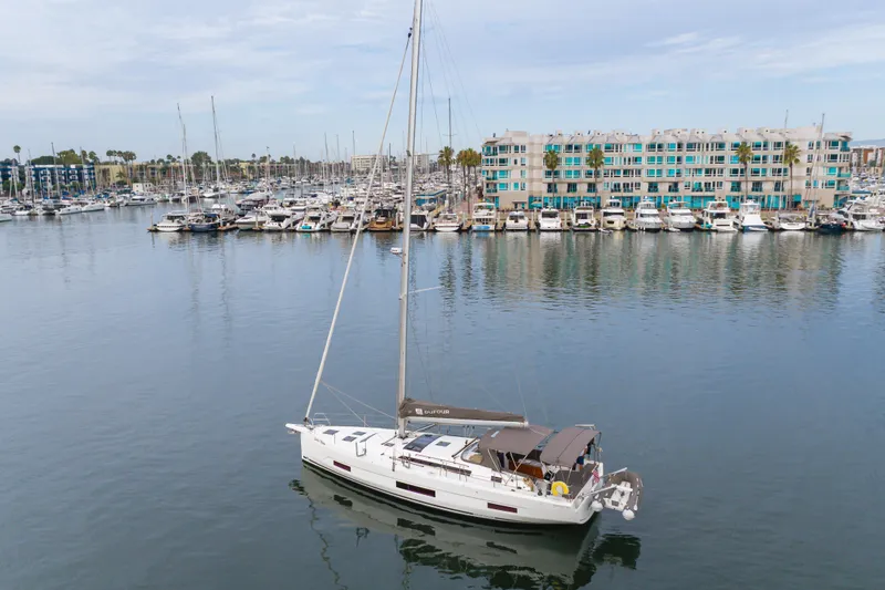 Slide: The Image of 2024 Dufour 470 sailboat in marina, calm waters, modern waterfront buildings. - 10