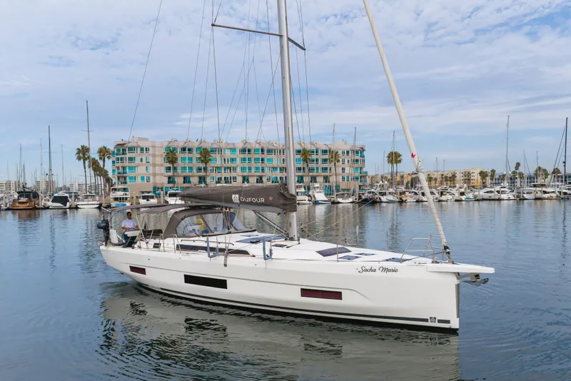 Slide: The Image of 2024 Dufour 470 sailboat docked in marina, modern design, calm waters, coastal backdrop. - 11