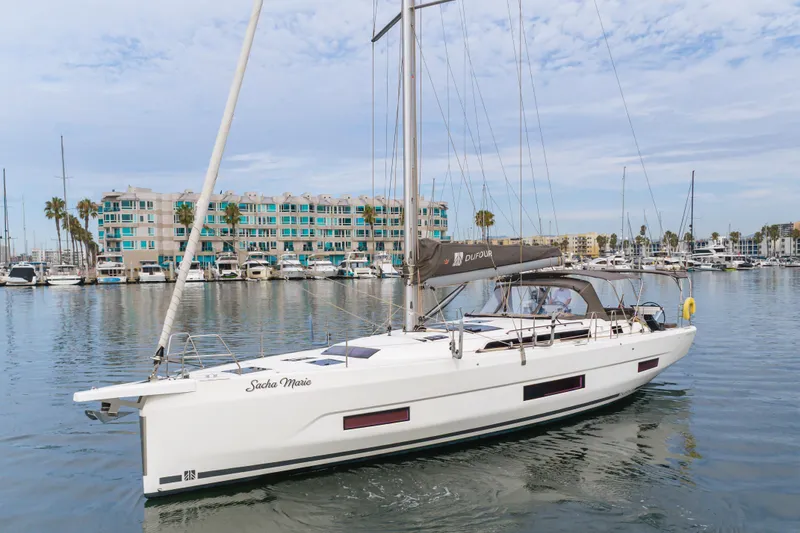 Slide: The Image of 2024 Dufour 470 sailboat docked in marina, modern design, calm waters, coastal buildings. - 12