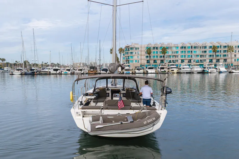 Slide: The Image of 2024 Dufour 470 yacht docked in marina, with modern buildings in the background. - 16