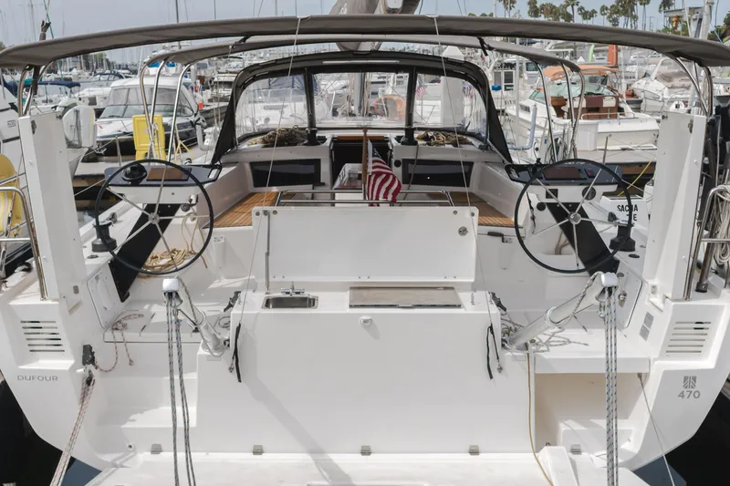 Slide: The Image of 2024 Dufour 470 yacht at marina, featuring dual steering wheels and spacious cockpit. - 17