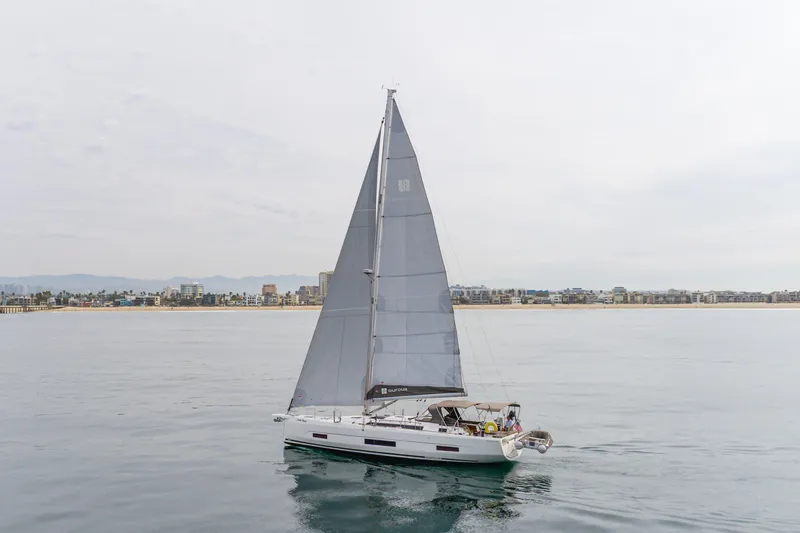 Slide: The Image of 2024 Dufour 470 sailboat cruising near a coastal city skyline. - 4