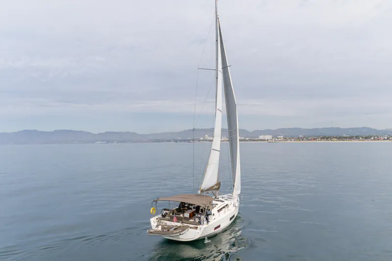 Slide: The Image of 2024 Dufour 470 sailboat cruising on calm waters near a coastal cityscape. - 6