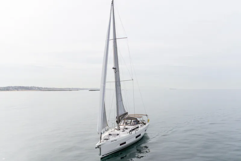 Slide: The Image of 2024 Dufour 470 sailboat cruising on calm waters under a cloudy sky. - 7