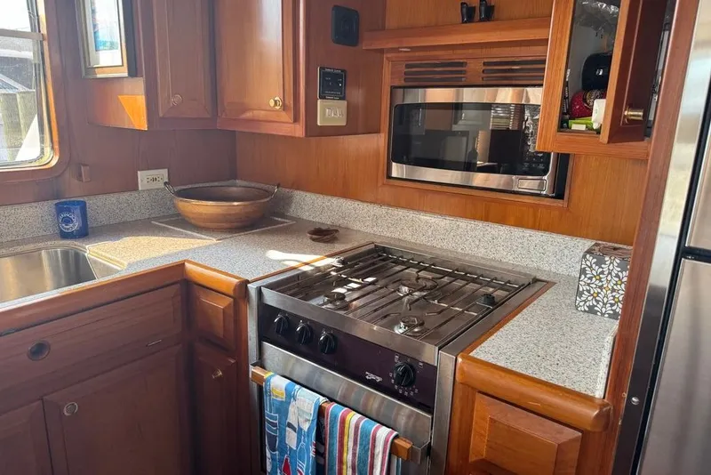 Slide: The Image of Galley kitchen in 2006 DeFever 52 Euro yacht with stove, microwave, and wooden cabinetry. - 26