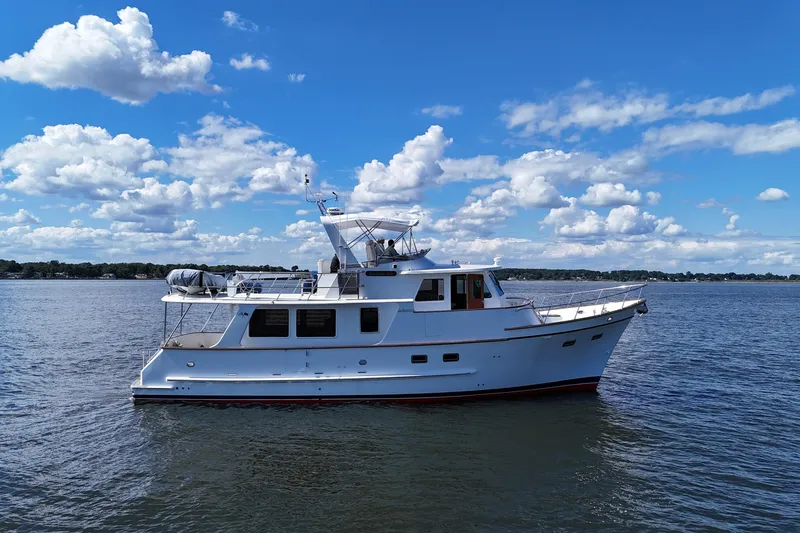 Slide: The Image of 2006 DeFever 52 Euro yacht on calm water under a blue sky with clouds. - 56