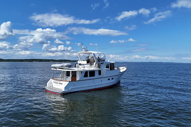 Slide: The Image of 2006 DeFever 52 Euro yacht cruising on a calm, scenic waterway under a clear blue sky. - 64
