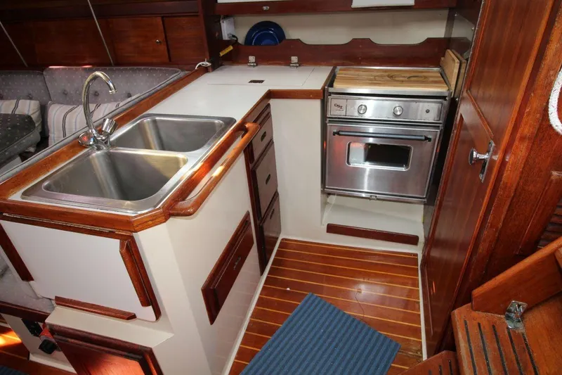 Slide: The Image of 1987 Catalina 34 yacht kitchen with double sink, stove, and wooden cabinetry. - 16