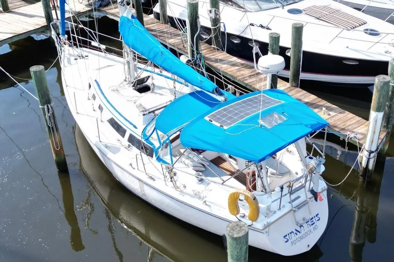 Slide: The Image of 1987 Catalina 34 sailboat docked, featuring blue covers and solar panel on deck. - 3