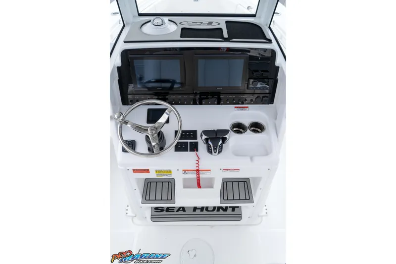 Slide: The Image of 2026 Sea Hunt Gamefish 25 helm with steering wheel, dual screens, and control panel. - 18