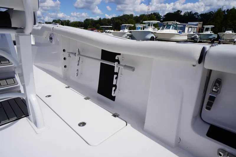 Slide: The Image of 2025 Tidewater 272 LXF boat interior with rod holder, sleek white design, and marina background. - 30