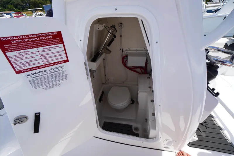 Slide: The Image of 2025 Tidewater 272 LXF boat interior with open door showing compact marine toilet. - 59