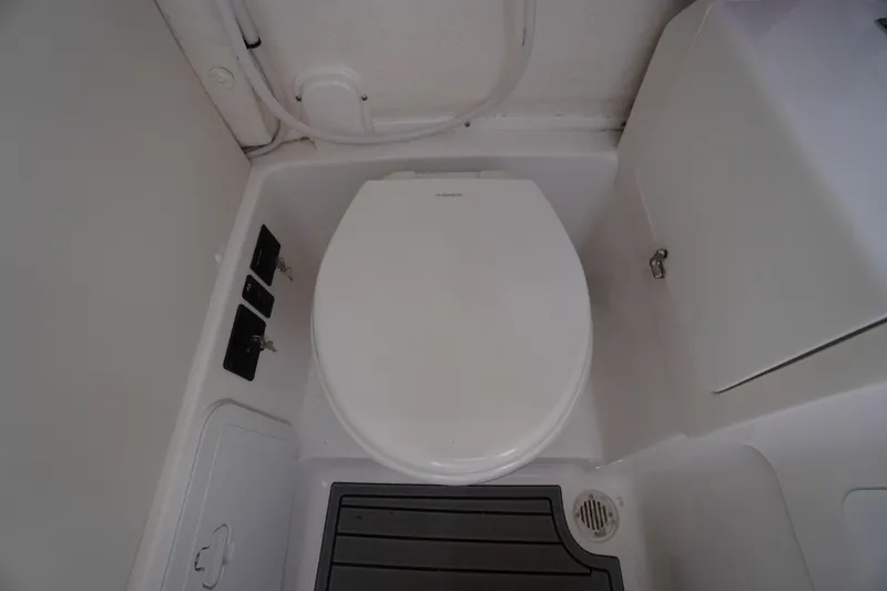 Slide: The Image of 2025 Tidewater 272 LXF boat bathroom with compact toilet and storage compartments. - 62