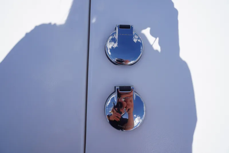 Slide: The Image of Close-up of chrome fixtures on a 2025 Tidewater 272 LXF boat, reflecting sky and shadows. - 76