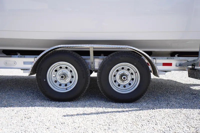 Slide: The Image of Trailer wheels of a 2025 Tidewater 272 LXF boat on gravel surface. - 89