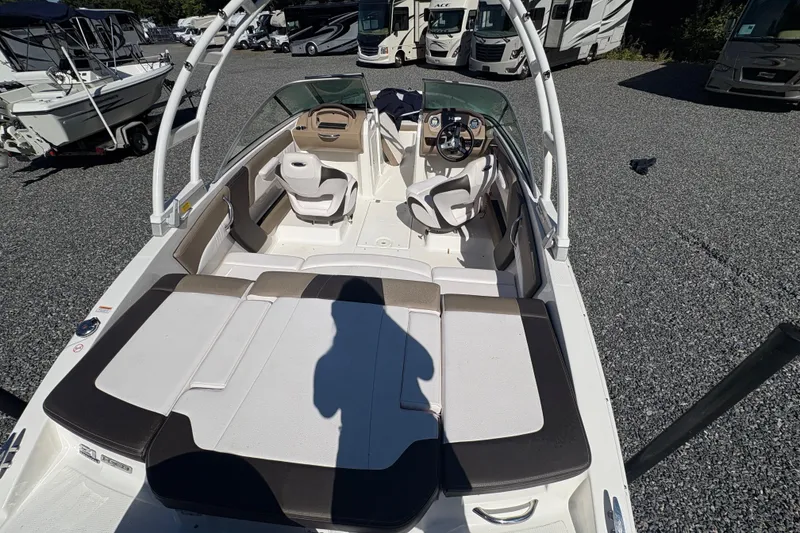 Slide: The Image of 2019 Chaparral 18 H2O Sport boat interior with seating and steering wheel, parked outdoors. - 7