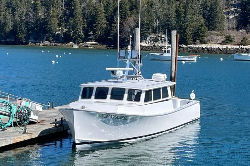 The Image of 2018 Mussle Ridge 46 boat docked in a scenic harbor with forested background. - 0