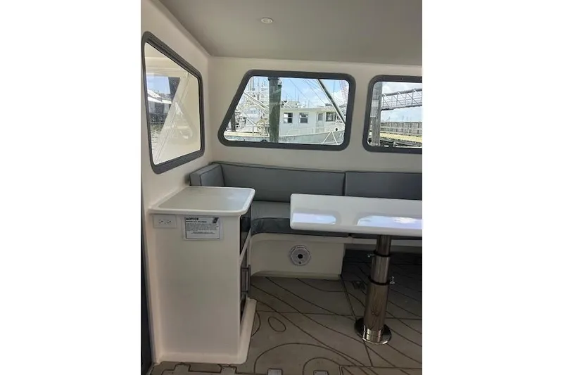 Slide: The Image of Interior of 2018 Mussle Ridge 46 boat with seating and table, featuring large windows. - 8