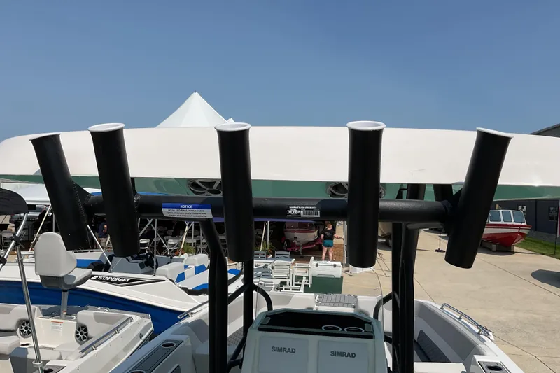 Slide: The Image of 2026 Starcraft SVX 231 OB CC boat with rod holders and Simrad electronics, docked outdoors. - 18